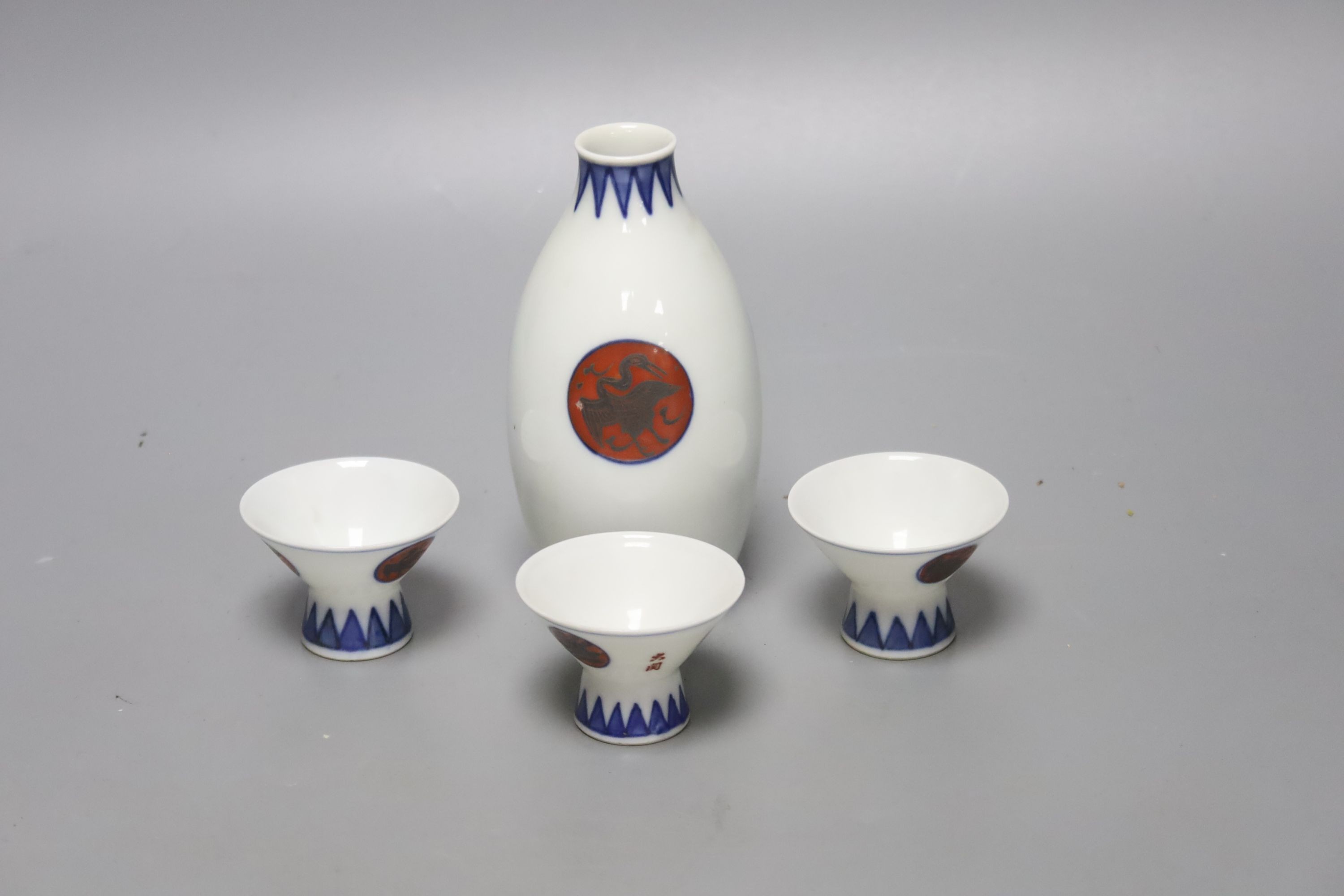 A Japanese blue and white porcelain sake flask, with associated cups, height 12cm